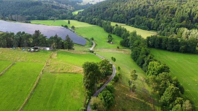 Drohnenflug &uuml;ber Tal mit Solarpark auf der linken Seite in Hessen, Deutschland