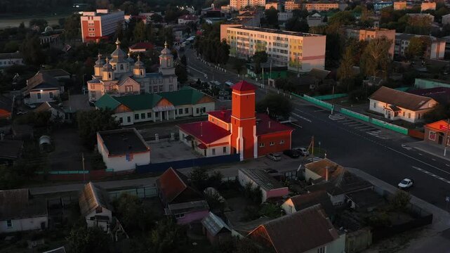 Aerial view Fire department of a stunning urban landscape with churches and a striking red tower at sunset. Dobrush city, Belarus