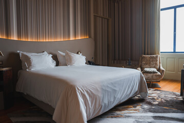 A spacious hotel room featuring a large bed with crisp white linens, ambient lighting, and...