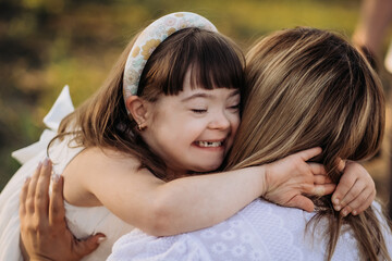 little girl with down syndrome hugs her mother