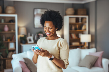Young woman using the mobile phone at home. Portrait of a happy and connected woman at home, who...