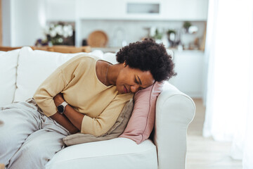 Cropped shot of an attractive young woman lying down on her bed and suffering from period pains at home. Ouch! My tummy! Woman with menstrual pain