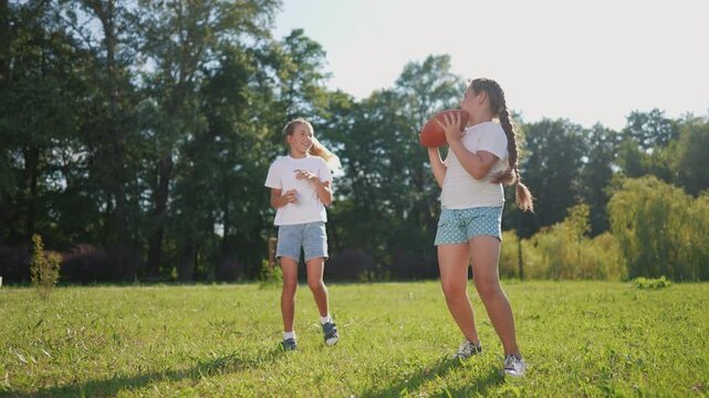 American children playing ball. American football sports concept. American football with children playing in a park. American football player and his children playing football in lifestyle park.