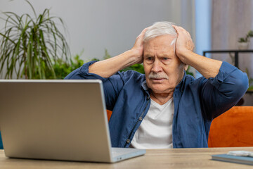 Displeased senior old man use laptop notebook typing browsing working loses becoming surprised...