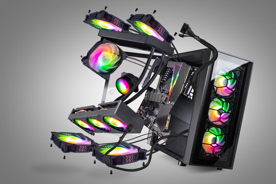 Black modern high end gaming computer with glass windows and bright colorful rainbow RGB LED lights grey background. flying parts and components pc in exploded view.