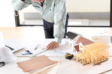 建築設計をする作業着姿の悩むアジア人男性