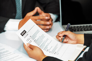 Human resources department manager reads CV resume document of an employee candidate at interview room. Job application, recruit and labor hiring concept. uds