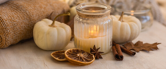 Atmospheric aroma candles with sweet spicy scent and white pumpkins on wooden tray, autumn bedroom decor. Autumn cozy home and hygge concept, place for relaxation, detention. Aromatherapy banner