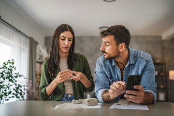 Couple learn from mobile phone how to make a clay figurine, pottery