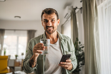 Portrait of adult men stand hold glass of water and mobile phone