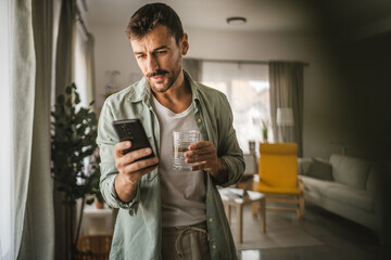Portrait of adult men stand hold glass of water and mobile phone