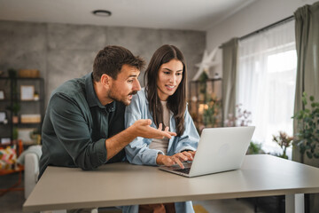 adult caucasian couple stand and use, study learn on laptop at home