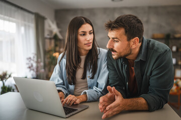 adult caucasian couple stand and use, study learn on laptop at home