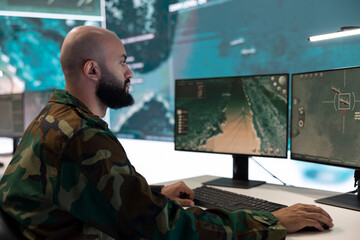 Infantry unit officer examines big data on pc in military control room, employing high tech anti...