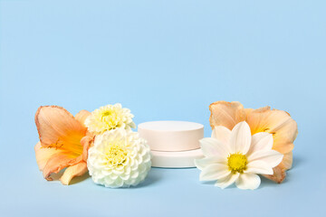 Concept scene stage showcase for new product, banner, promotion sale, cosmetic, presentation. White round podium and orange lily flowers, white dahlia flowers on blue background.