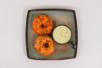 Medhu Vadai is a traditional South Indian delicacy known for its exquisite taste and crispy texture. Vadai, medu vada, uzhunnu Vada, with coconut chutney on plate served hot. 