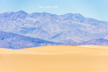Sand dunes against the backdrop of mountains and sky in Death Valley, California