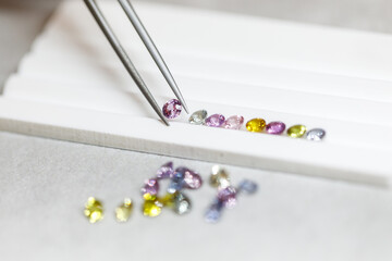 multi-colored sapphires. Gems. A jeweler selects precious stones using a tool. View from above. Macro photography.