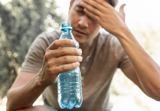 Man drinking water in extreme summer heat, person drinks from water bottle replenish fluids	