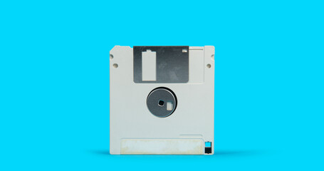 old white plastic square computer floppy disk on a blue surface against blue background