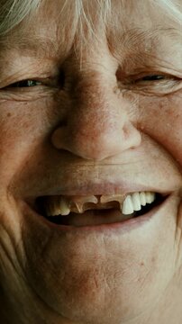 Portrait of cheerful old lady with falling out denture looking at camera. Close-up of toothless old lady's face and eyes. vertical video