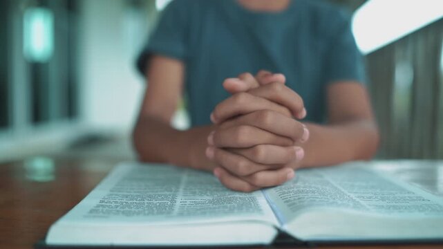 Close up hands of christian reading Bible and praying on at wooden table in morning.