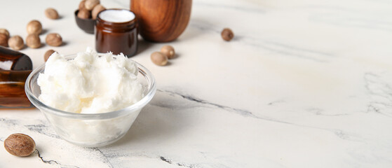 Glass bowl of shea butter and nuts on white background