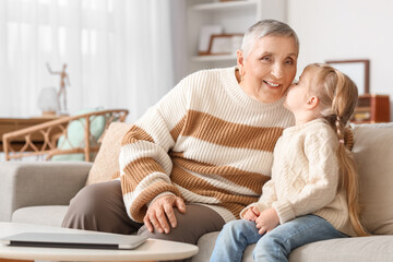 Cute little girl kissing her granny at home