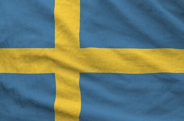 Sweden flag depicted on folded wavy fabric of old cloth close up