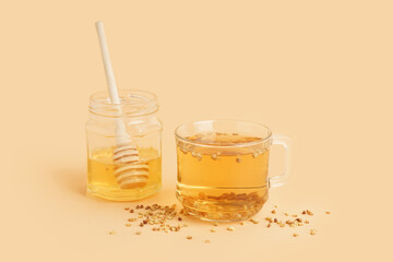Glass cup of fresh tasty buckwheat tea and honey on beige background