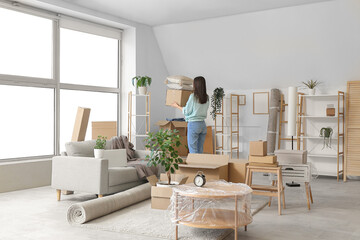 Young woman with cardboard boxes in light living room on moving day