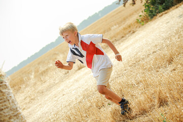 Young Boy Joyfully Running Through a Golden Wheat Field on a Sunny Day in Summer