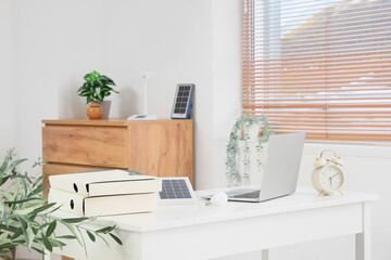 Engineer's workplace with laptop, light bulb and portable solar panel in office