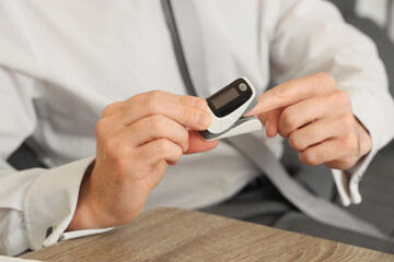 Young businessman with pulse oximeter in office, closeup