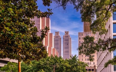 Urban cityscape of Atlanta with trees framing the view of skyscrapers under a clear blue sky