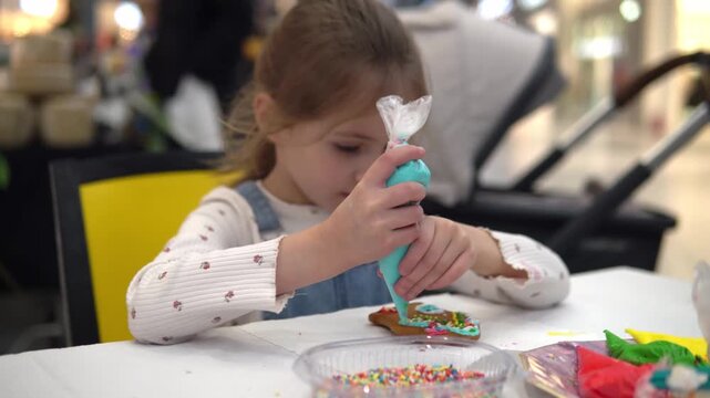 A joyful child is decorating cookies with colorful
