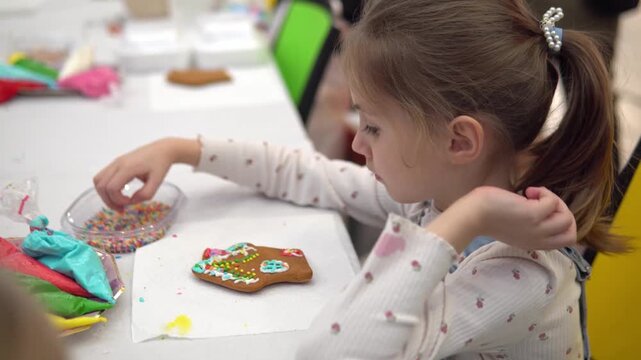 A joyful child decorates a gingerbread cookie duri