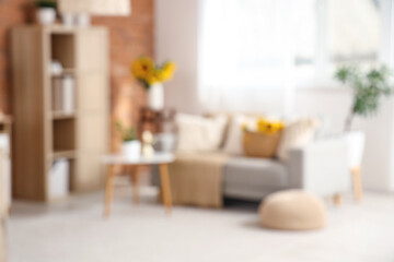 Blurred view of stylish living room with grey sofa and beautiful sunflowers