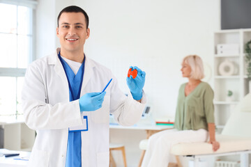 Male endocrinologist with thyroid gland model in clinic