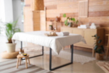 Blurred view of spa salon with massage couch, drawers and shelf unit