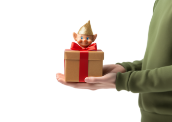 Elf Figurine Atop Gold Gift Box With Red Ribbon Held By Person In Green Sweater