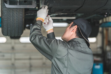 リフトに上がる車両の下で整備・点検・作業をする自動車整備士の男性
