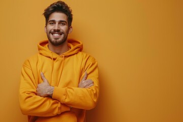 Obraz premium Youthful Joy in Tech: A Portrait of a Happy Young Man in Casual Hoodie Giving a Thumbs Up in a Simulated Workspace, Isolated on a Vibrant Yellow-Orange Background.
