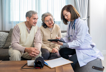 asian senior couple concentrate to listen a young female health care personnel who using tablet computer provide health information giving advice in the room at home