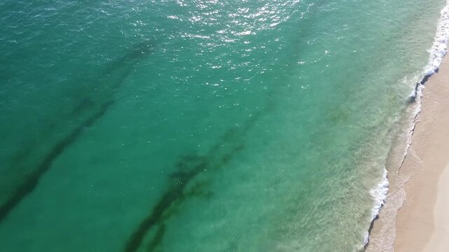 Aerial view of the beautiful turquoise sea with algae in Comporta, Portugal