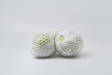 The green guava fruit is covered plastic is on a white background