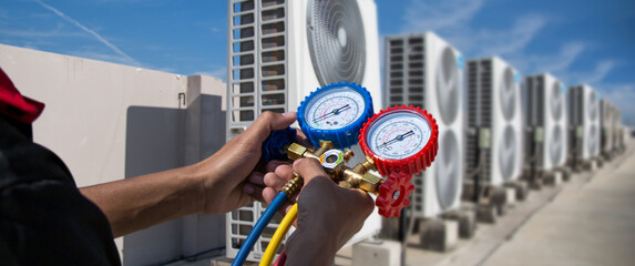 Air Conditioning service technician using measuring manifold gauge checking refrigerant and filling...