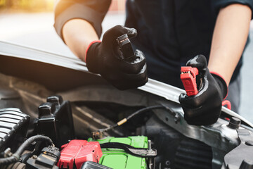 Hand car mechanic holding car booster cables for jump start car for empty battery dead and low voltage power problem or fix and service maintenance accident assistance engine doesn't start.