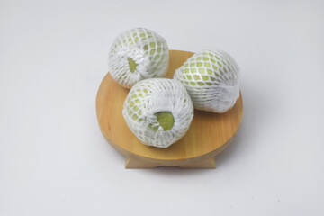 The green guava fruit is covered plastic is on a white background