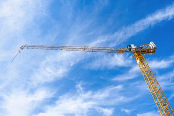 Tower crane working in construction site and stand out from the cloudy bright blue sky